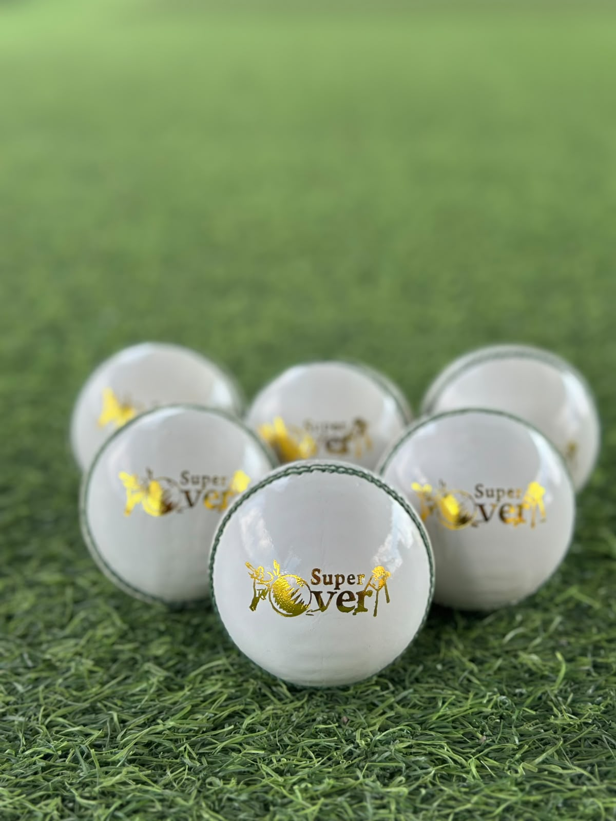 Super Over branded white cricket balls arranged on the practice turf